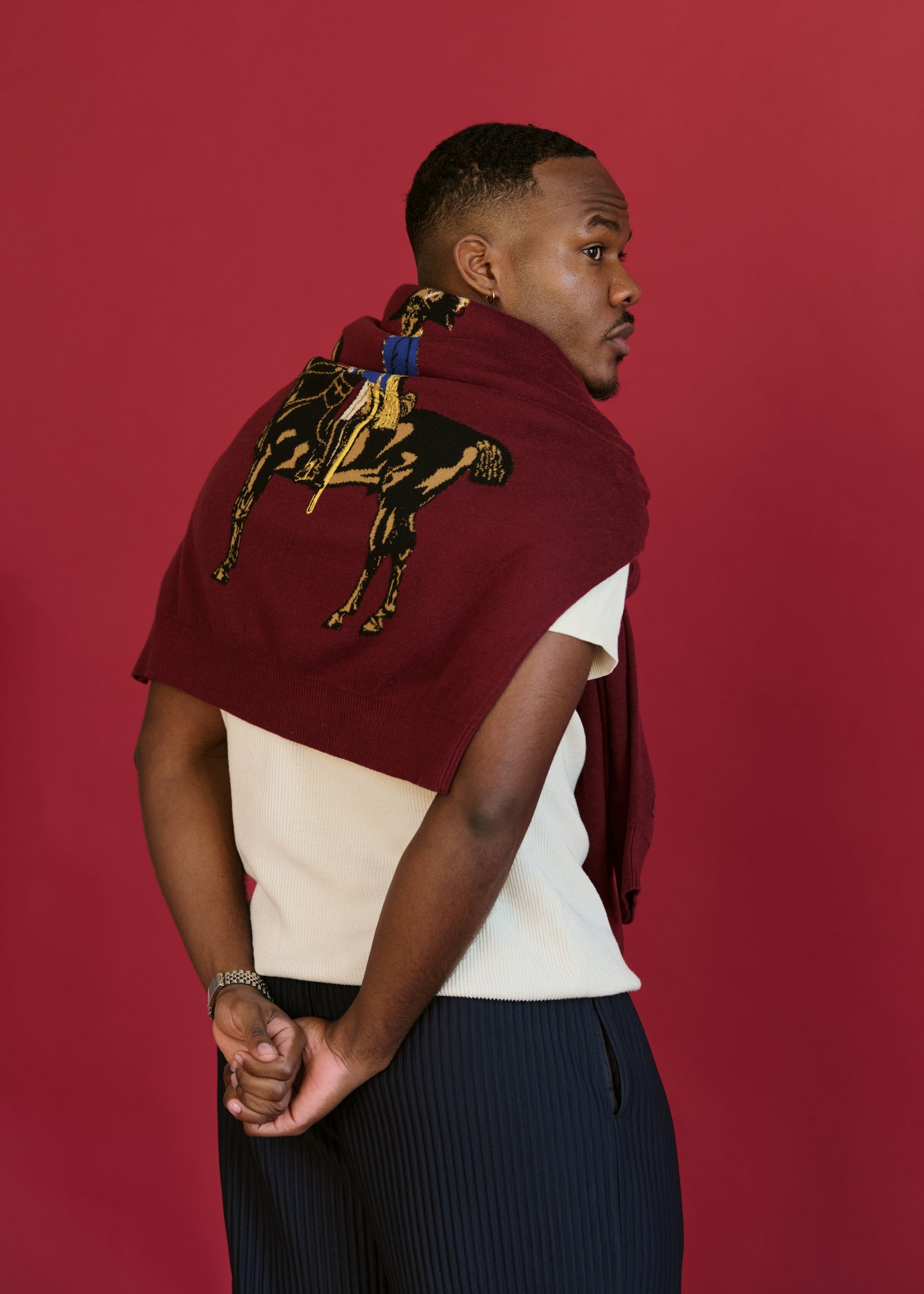 Back view of the Toussaint Sweater in burgundy, draped over shoulders to highlight jacquard-knit graphic of Toussaint Louverture on horseback